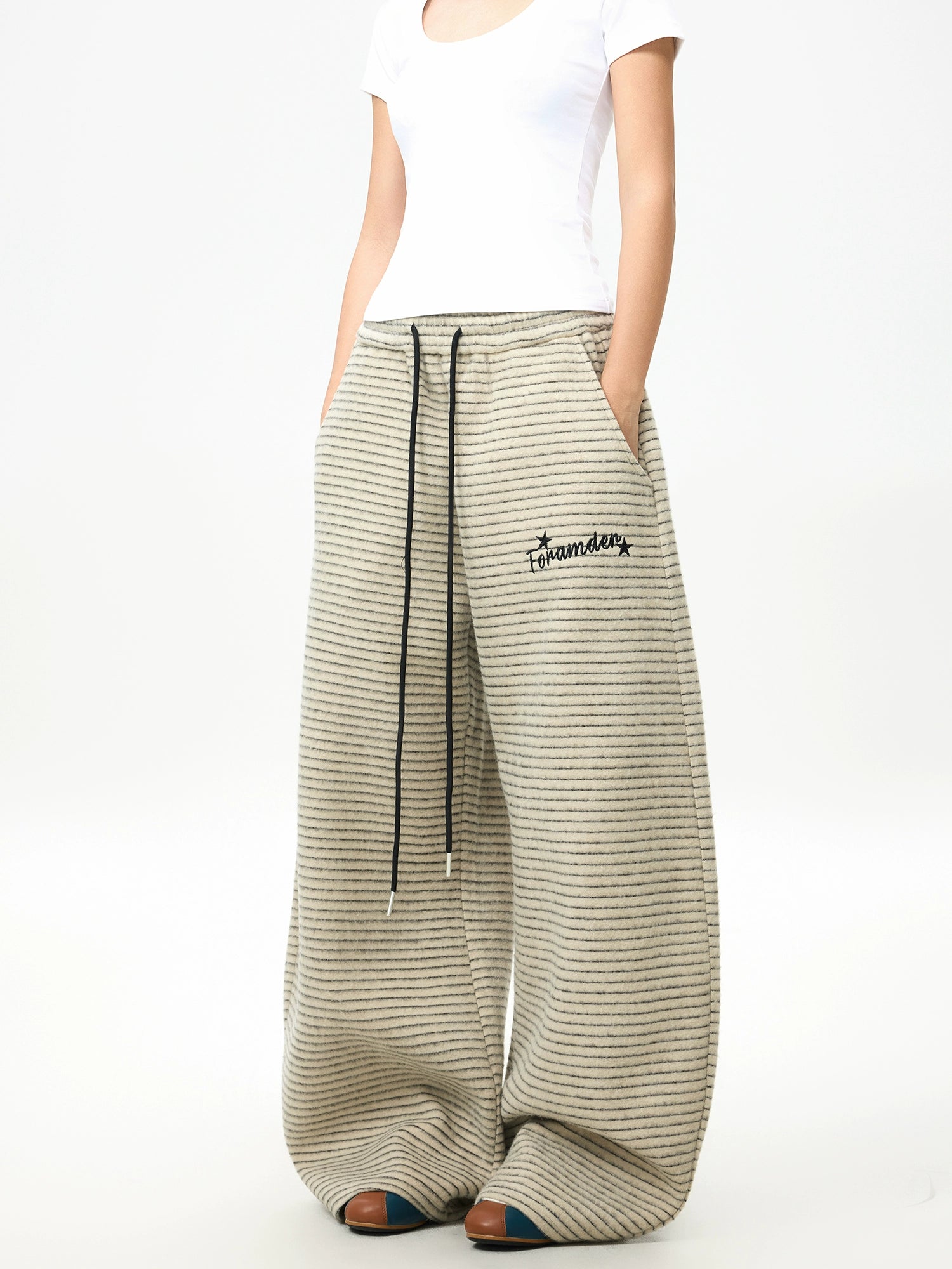 Front view of relaxed striped fleece wide-leg pants with elastic drawstring waistband, horizontal knit texture, and embroidered detail