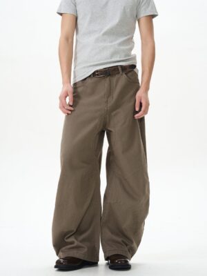 Brown skater wide leg streetwear pants shown in a full front view with a relaxed baggy denim silhouette, grey tee, and leather belt