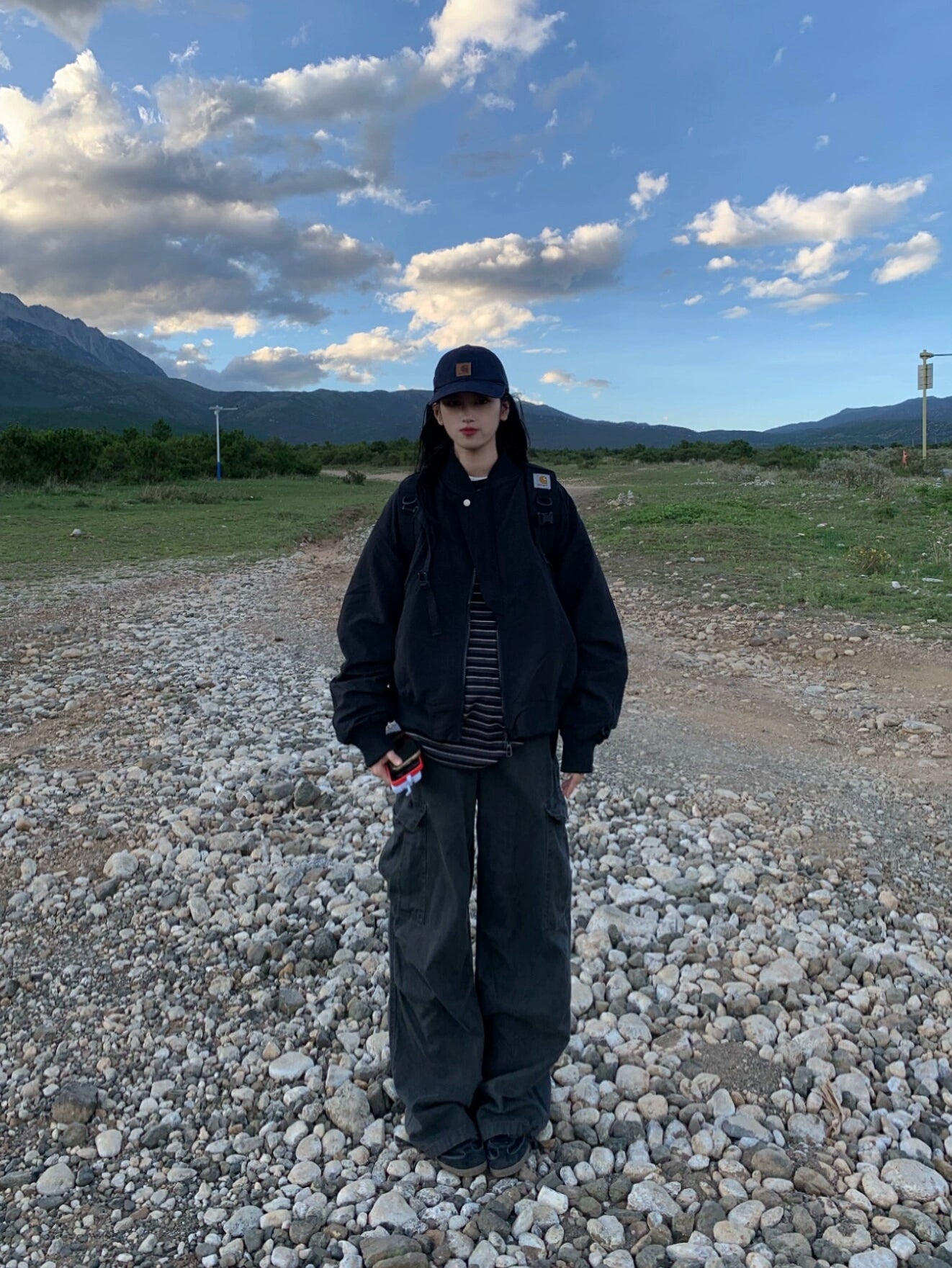 Oversized black flight bomber jacket with relaxed silhouette layered over a striped top and wide-leg cargo pants
