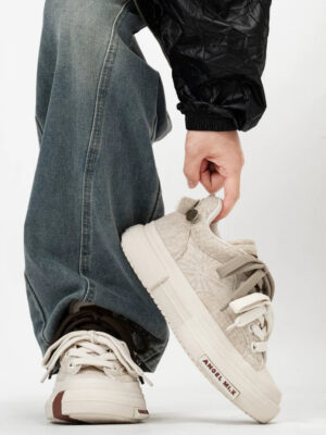 Close-up side view of textured beige fuzzy platform sneakers with neutral laces and cream rubber sole styled with loose jeans