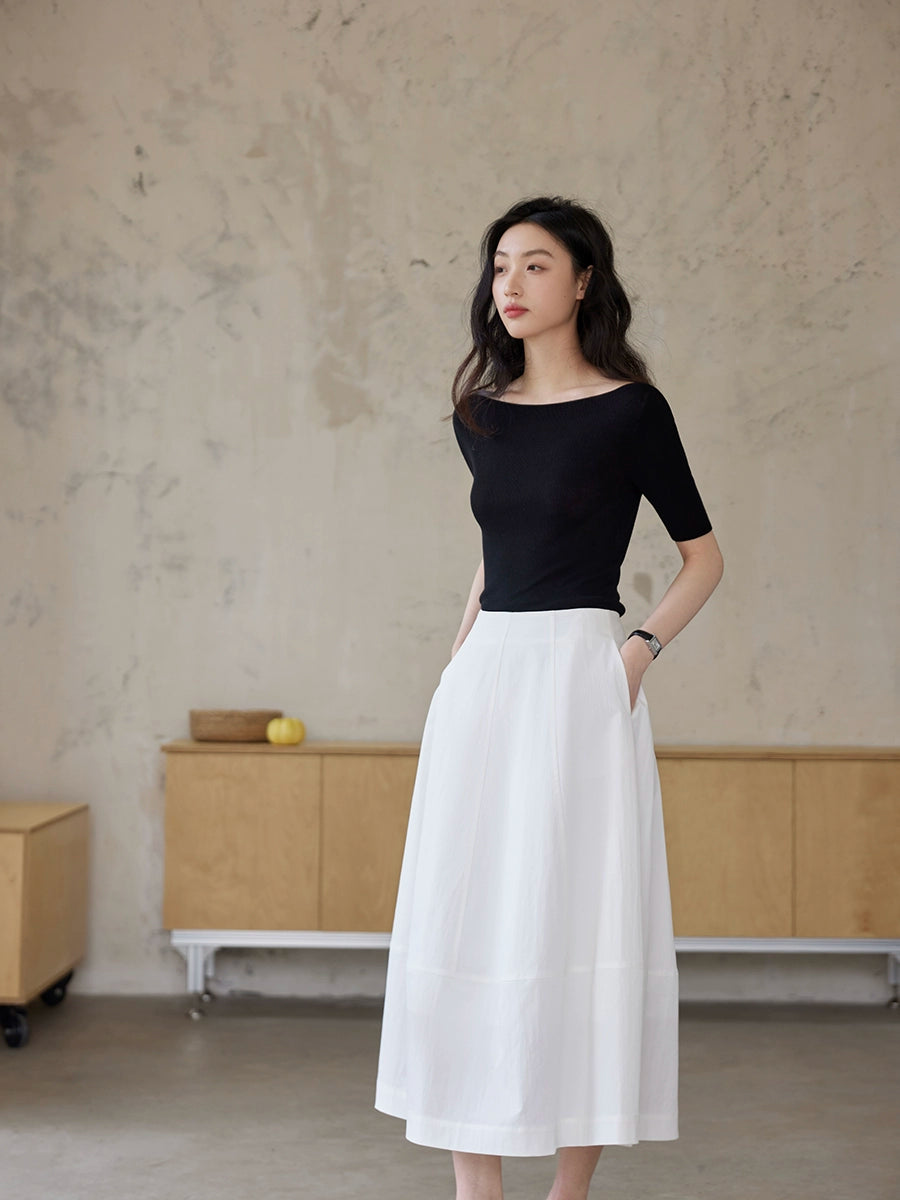 Black fitted boat neck knit top in side full body view paired with a flowing white midi skirt for Seoul minimalist style
