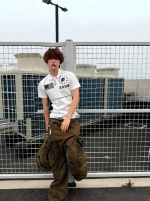 Full body view of a white 2002 varsity graphic polo shirt styled with cargo pants in a modern rooftop streetwear outfit