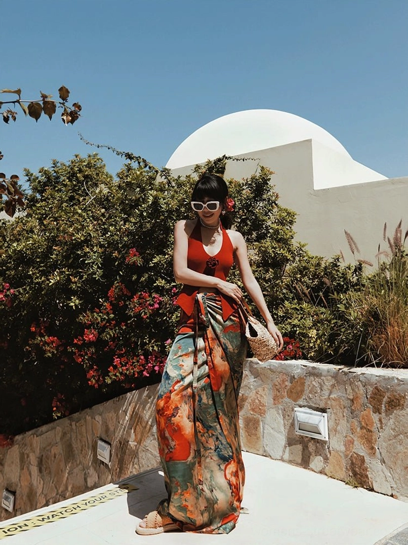 Abstract watercolor print tie-waist maxi skirt styled with a red halter top in a Mediterranean courtyard with stone walls and bougainvillea