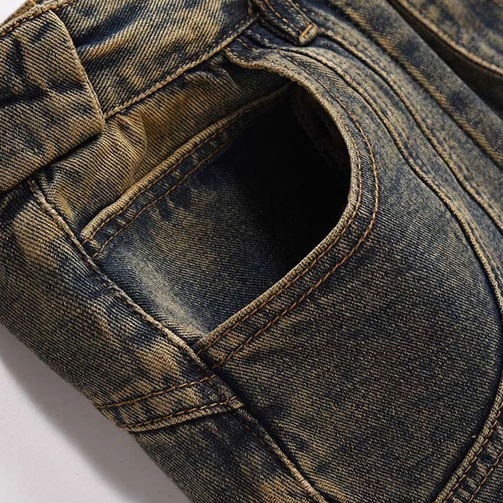 Close-up of acid wash denim jeans front pocket showing contrast topstitching, thick twill texture, and worn yellow vintage wash details