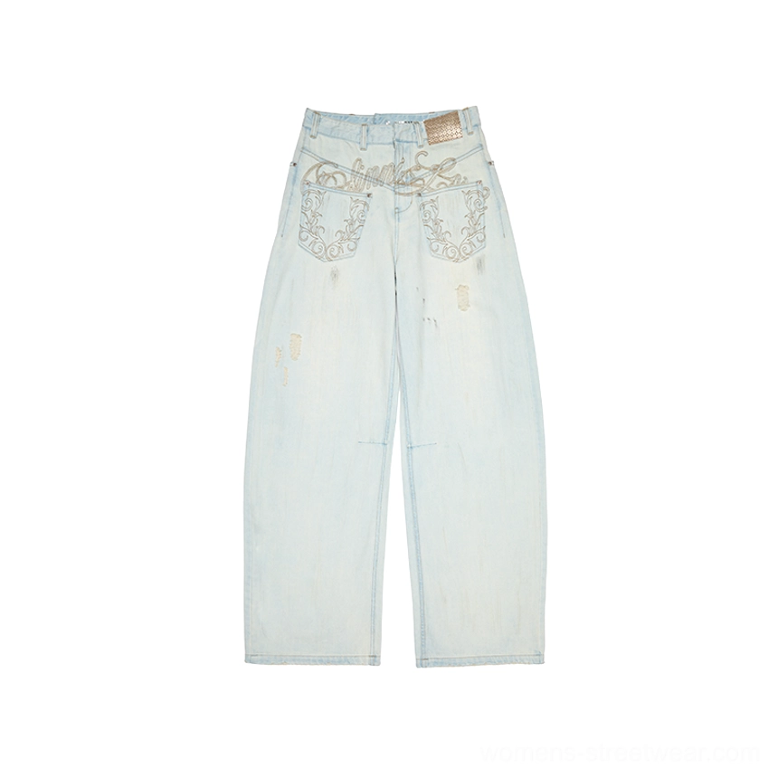 Light acid wash distressed arc-leg jeans displayed flat with vintage fading, embroidered waistband and pocket details, and loose wide legs