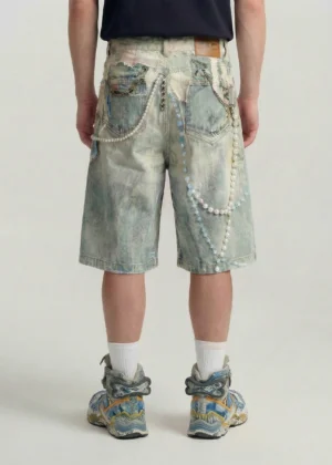 Back view of faded blue decorated denim jorts with dual pockets pearl chain accents and waistband patch