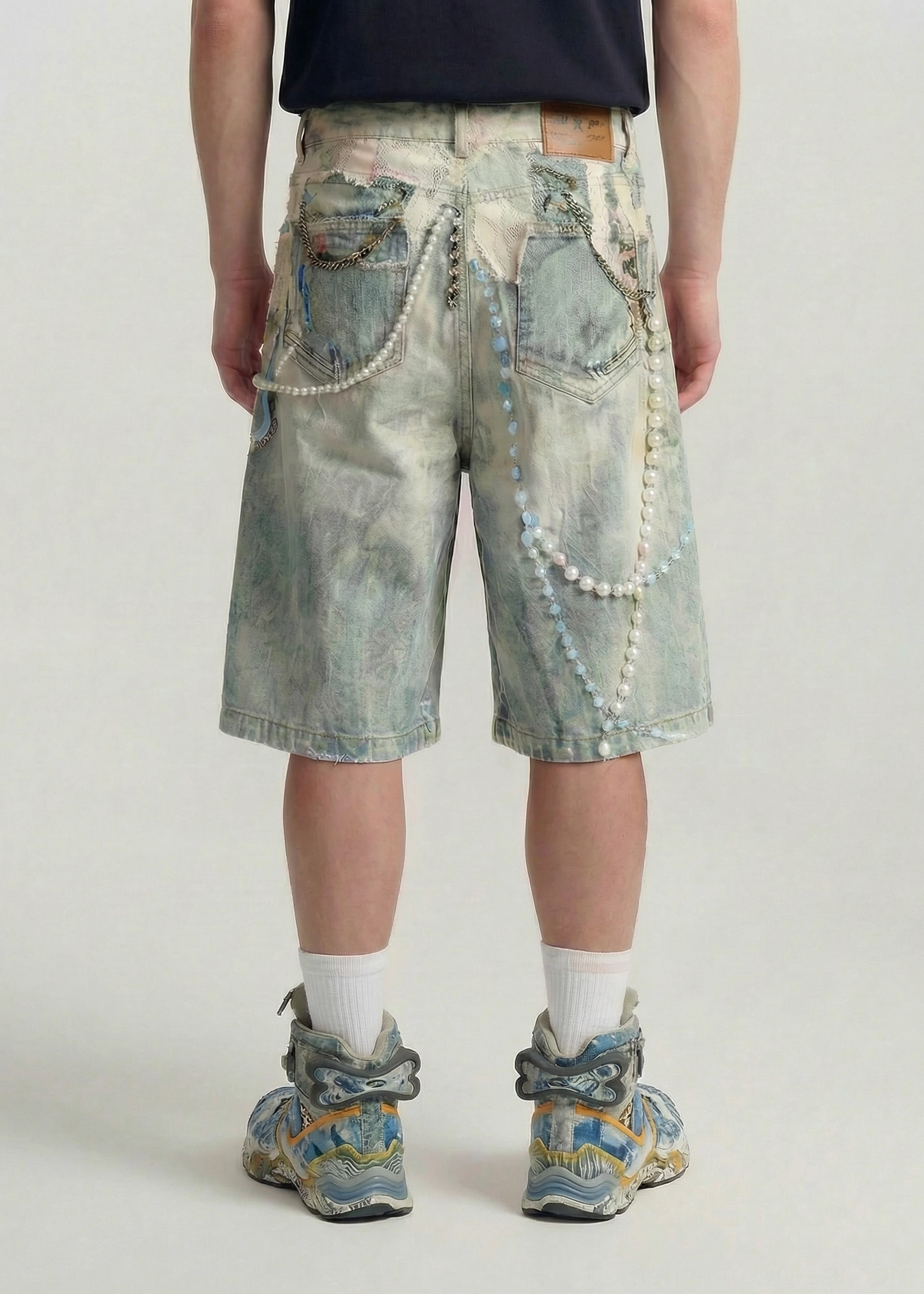Back view of faded blue decorated denim jorts with dual pockets pearl chain accents and waistband patch