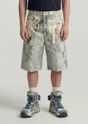 Front view of acid wash blue pearl chain embroidered denim jorts worn with a black t-shirt and high-top sneakers