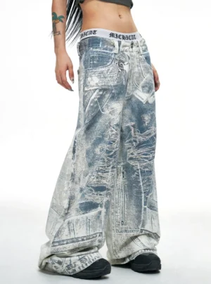 Low front side view of blue acid-wash wide-leg baggy jeans with distressed denim texture, exposed waistband treatment, and oversized streetwear silhouette