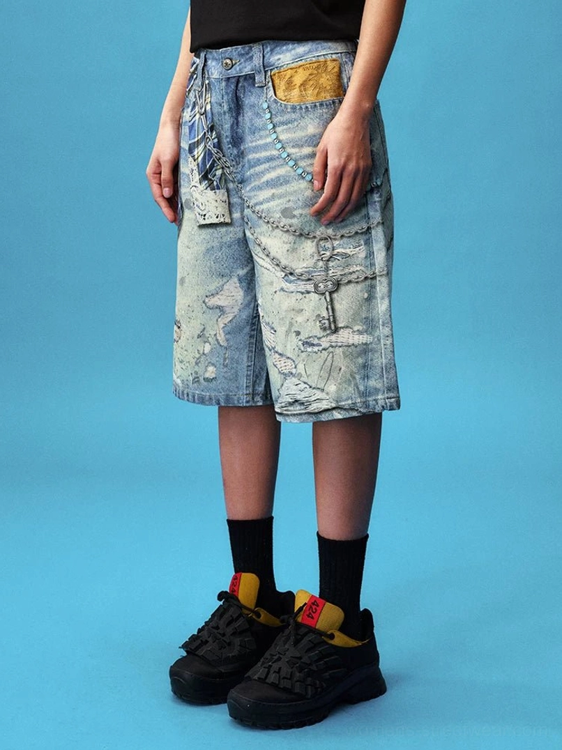 Side view of acid washed plaid chain denim jorts styled with a black top and chunky sneakers, highlighting the relaxed wide-leg streetwear fit