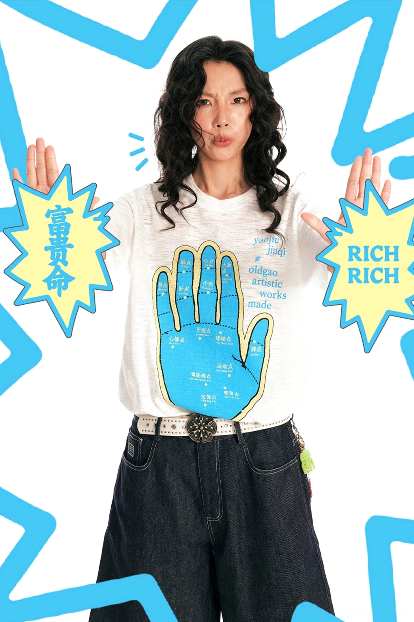 Female model styling white blue hand acupuncture graphic tee with dark denim and studded belt
