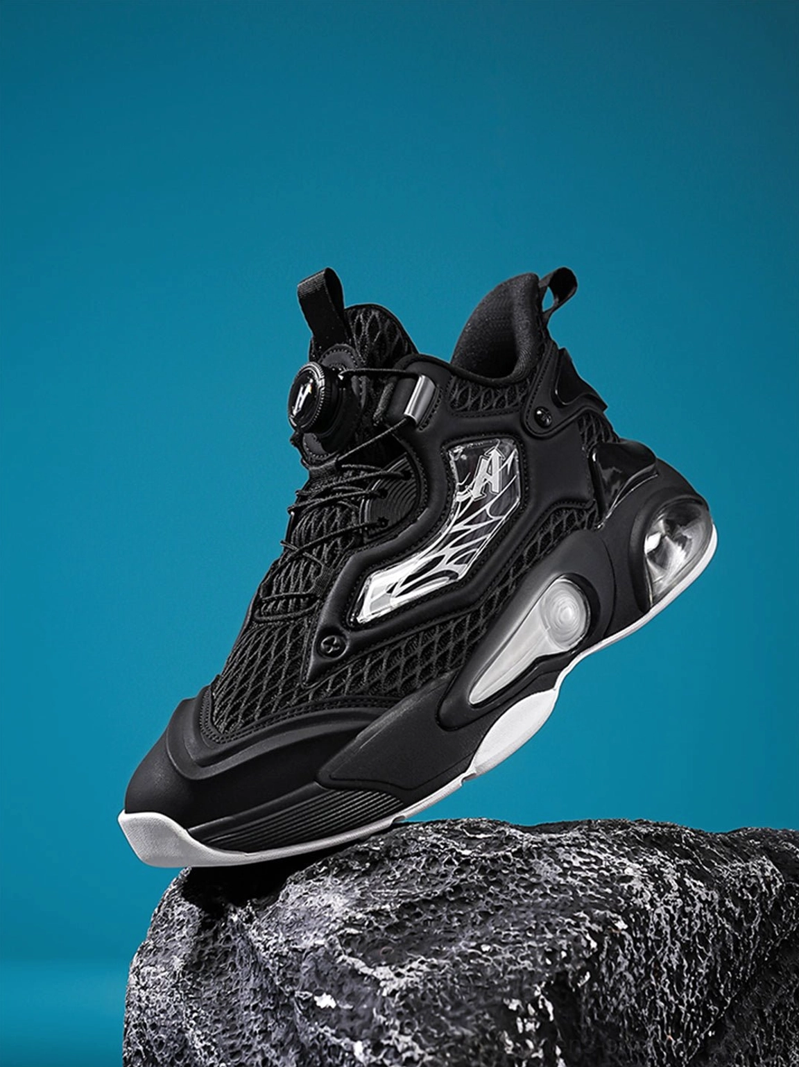 All-black air cushion runner sneakers displayed on a rocky prop with breathable mesh and rotary lacing