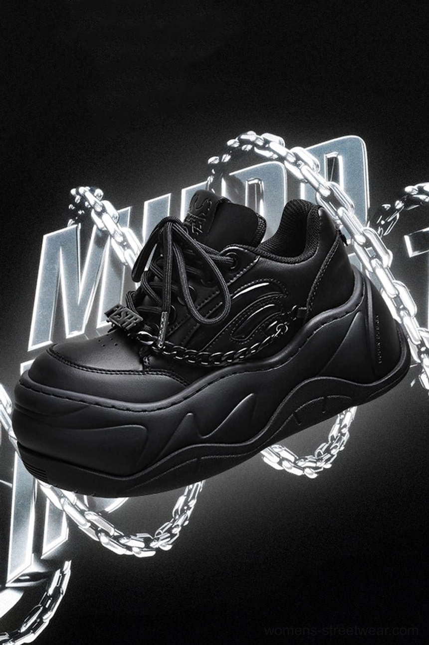 Promotional close-up of all-black chunky chain sneakers floating against a neon graphic background with matte leather upper and silver accents