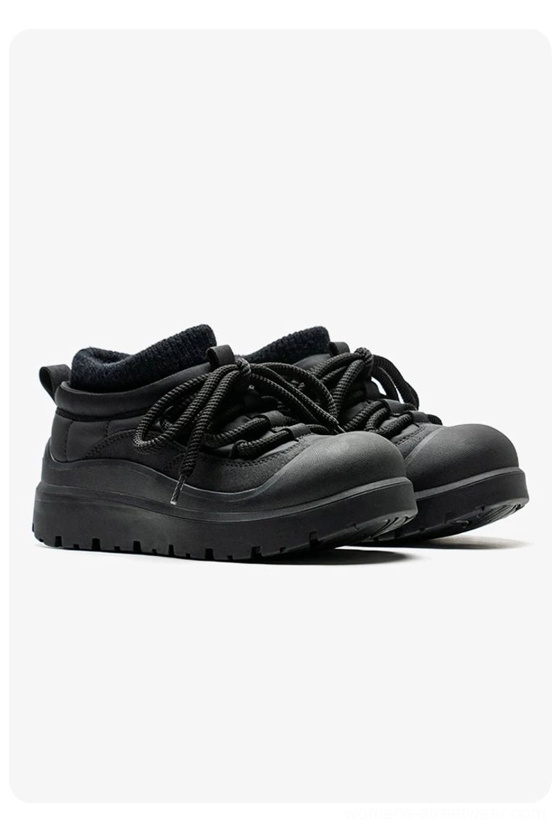 Front three-quarter product view of all-black fleece-lined platform sneakers with matte finish, rounded toe, and chunky sole
