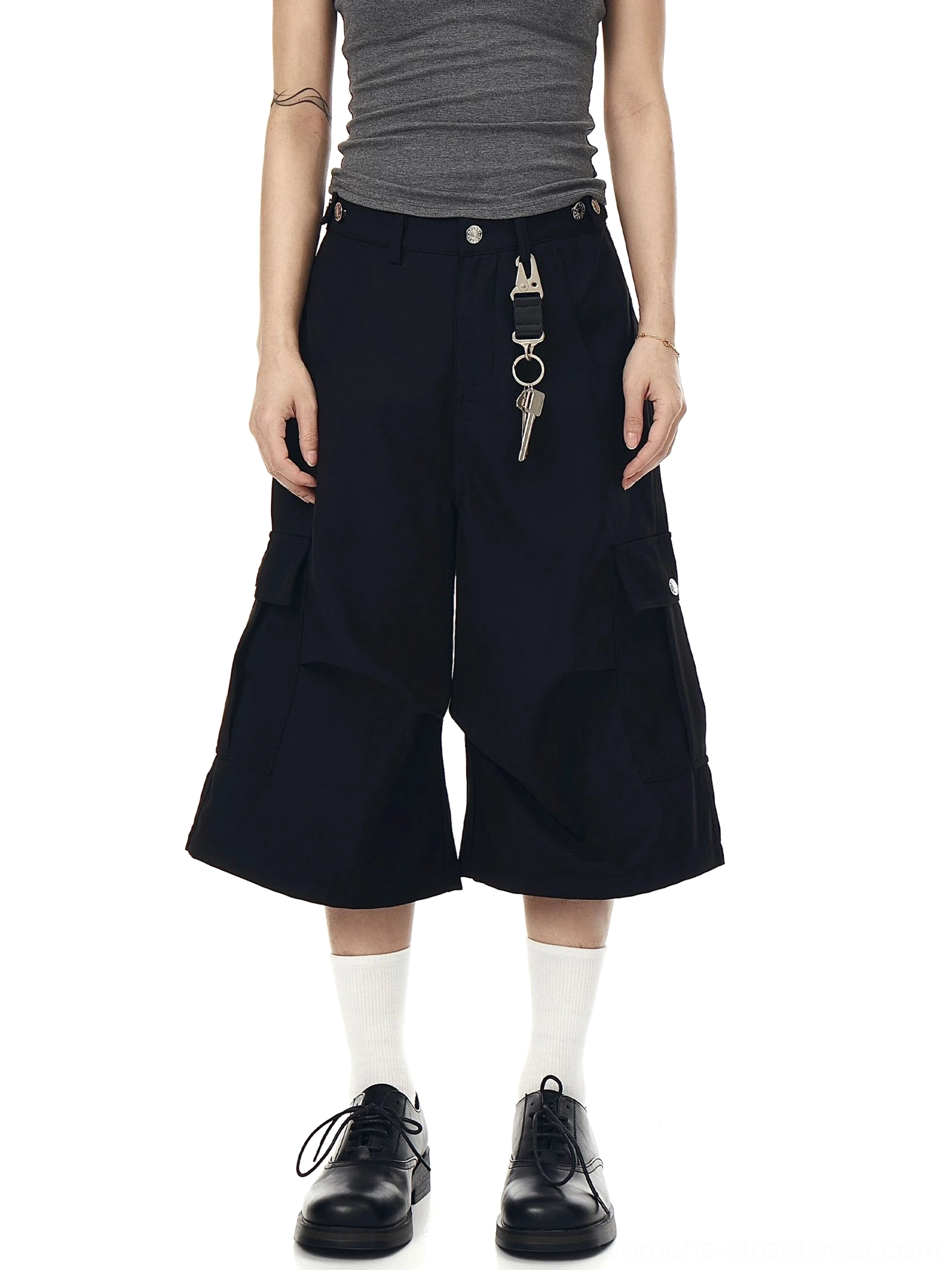 Front view of all-black oversized cargo shorts with cropped wide legs, side utility pockets, and minimalist streetwear styling
