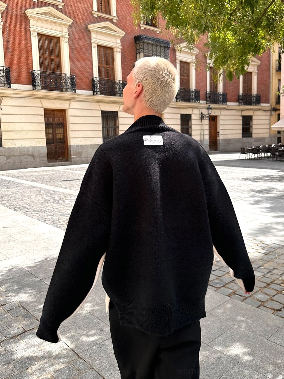 Back view of all black oversized V-neck racing stripe knit sweater with relaxed drop shoulder streetwear fit