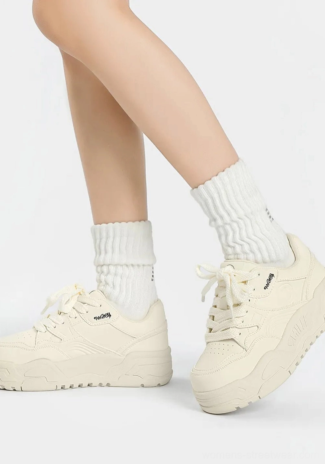 All-white platform skate sneakers shown from a three-quarter side angle with clean streamlined upper and printed tongue detail