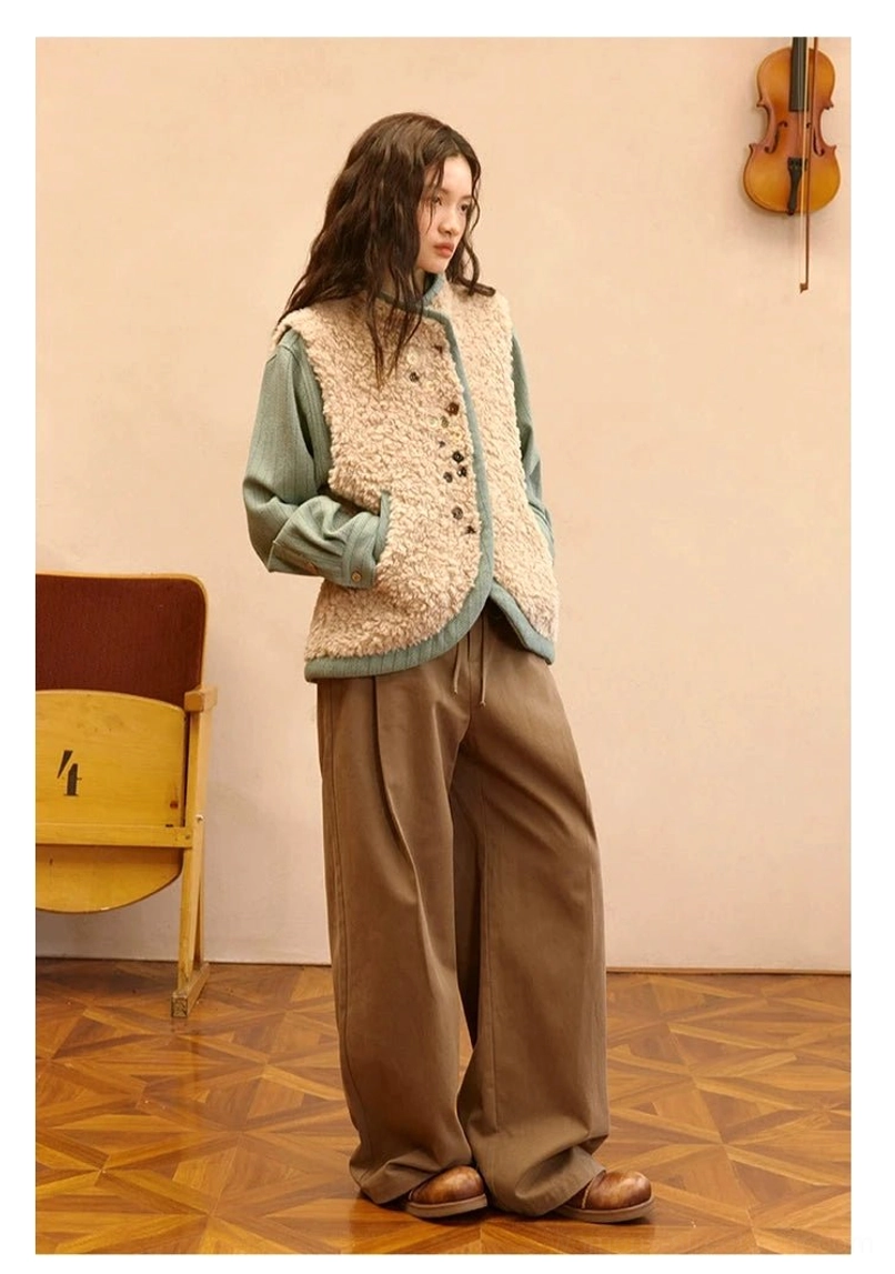 Almond beige sherpa vest with green contrast trim styled with wide-leg brown trousers in an artistic vintage studio