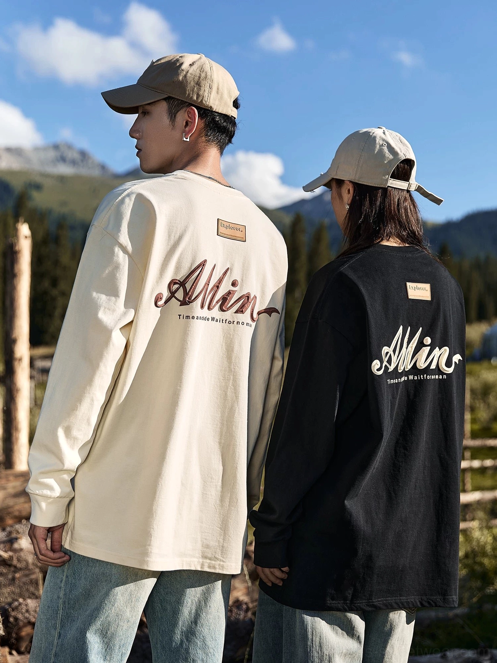 Rear view of ivory and black oversized alpine script long sleeve streetwear tees with large back graphics