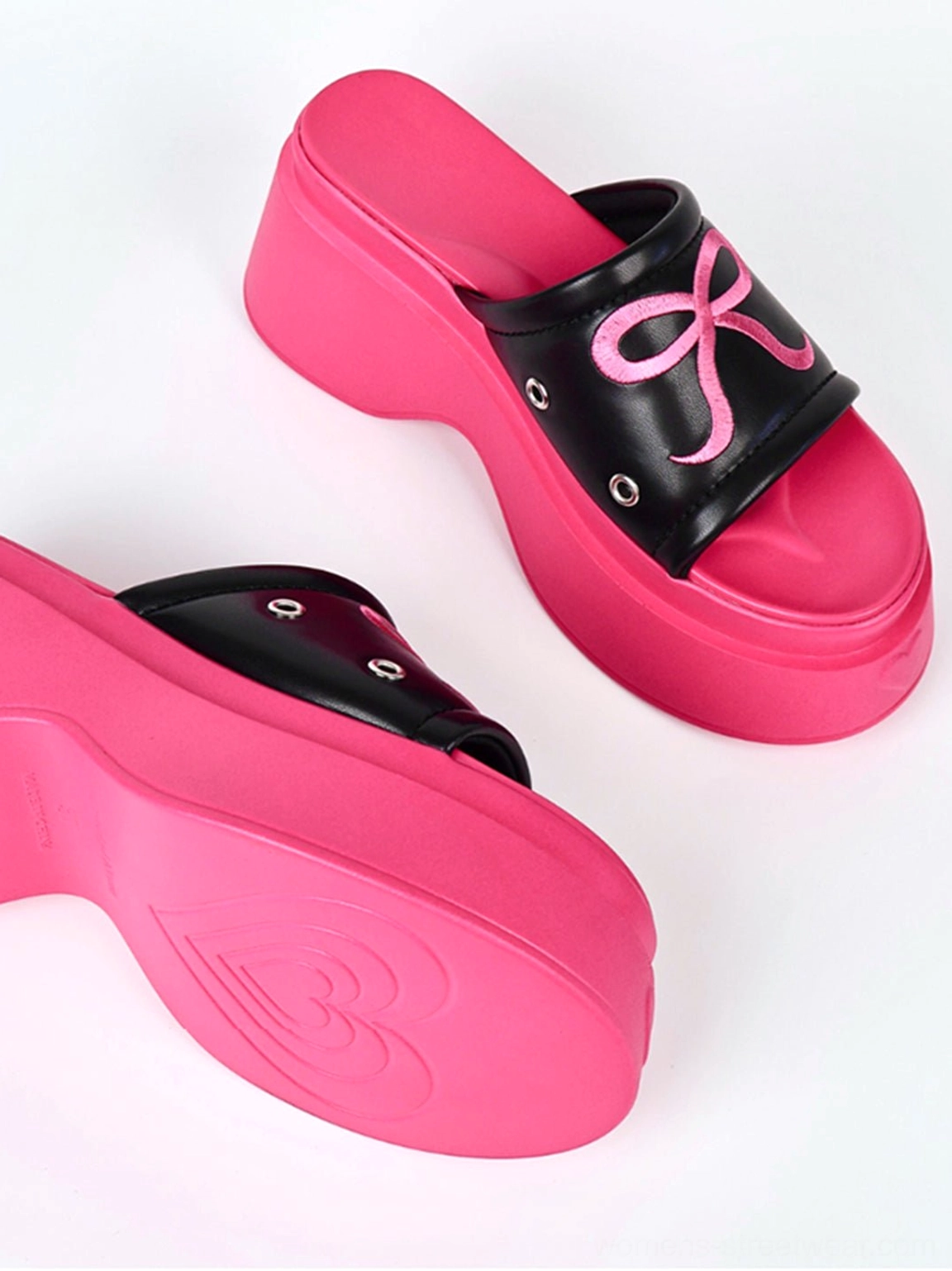Angled side view of hot pink bow platform slide sandals showing the sculpted sole and decorative outsole pattern