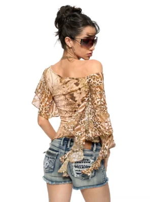 Back view of an animal print one-shoulder ruffle top with flowing sleeves, uneven hem, and low-rise embroidered denim shorts