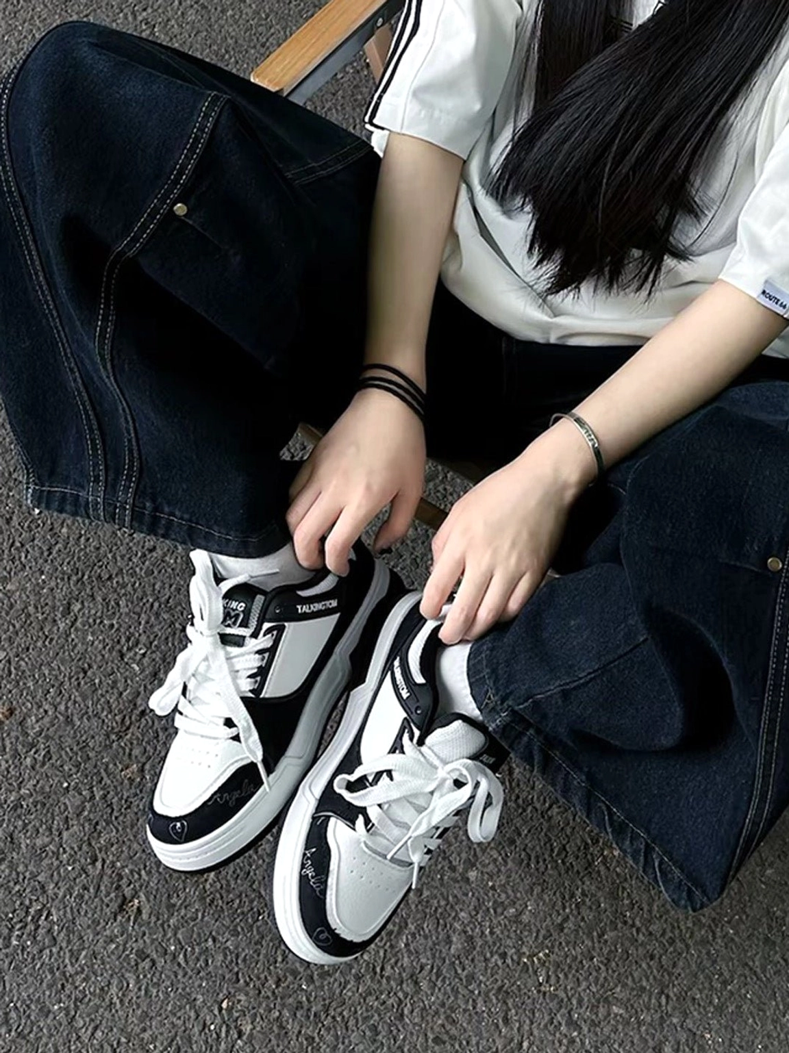 Anime cat graphic low-top sneakers worn with baggy dark jeans and striped shirt in a casual streetwear outfit