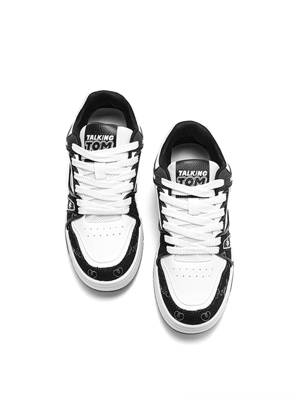 Top view of black and white anime cat print low-top sneakers with white toe boxes and graphic tongue details