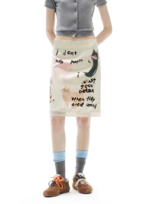 Front view of an apricot cream anti-social kitty scribble print midi pencil skirt styled with a cropped grey top, retro socks, and brown sneakers