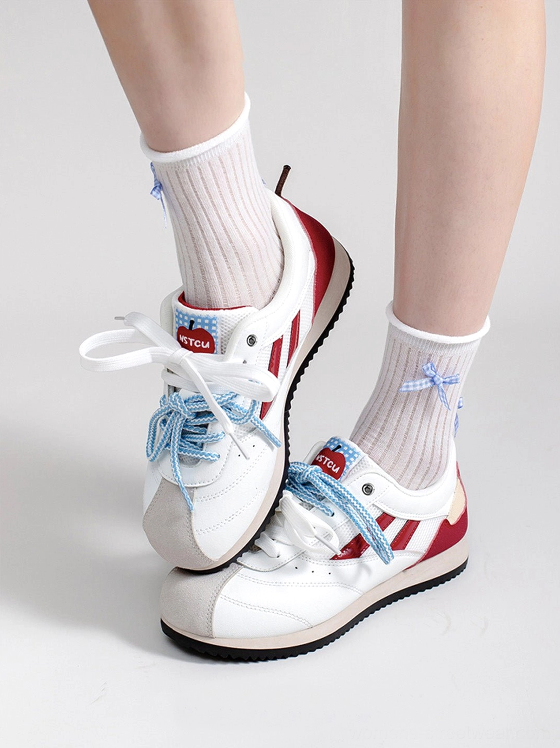 Detailed view of women’s apple detail red mesh retro runner sneakers with white mesh upper and wine red accents