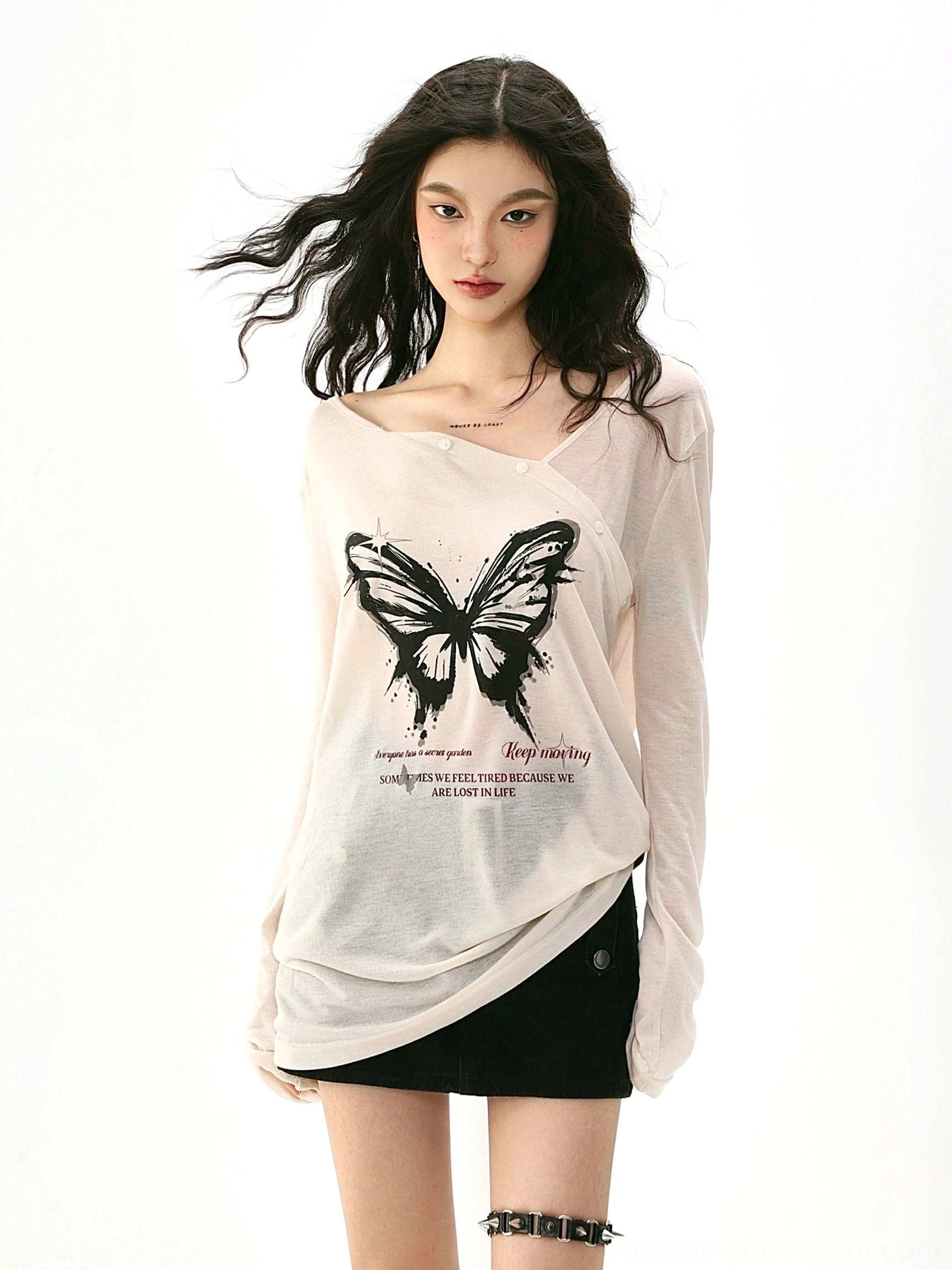 Close up front view of an apricot asymmetric neckline butterfly print long sleeve streetwear top with a draped hem and bold black graphic details
