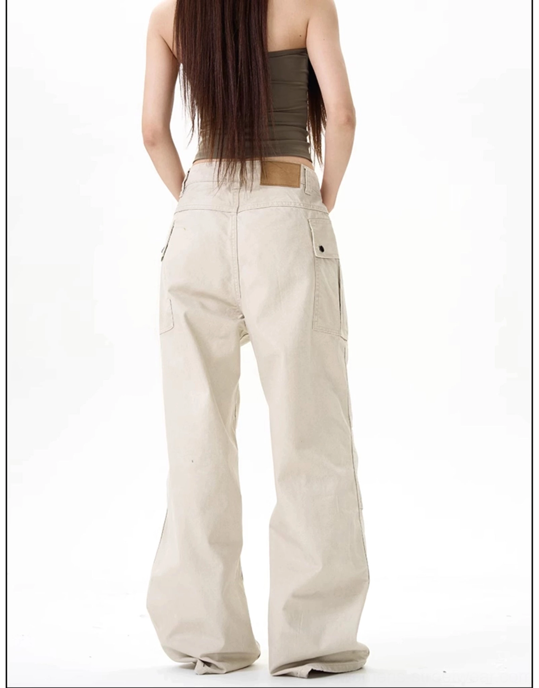 Back view of apricot beige wide-leg cargo pants with rear leather waist patch, flap back pockets, and relaxed fit