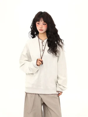 Apricot contrast stitch oversized Henley streetwear sweatshirt front view styled with beige wide-leg trousers