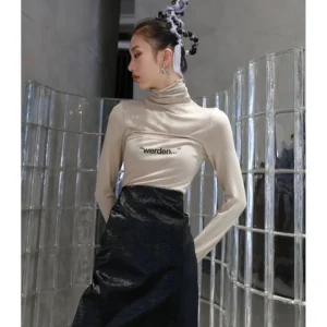 Apricot cutout turtleneck graphic top styled with a black faux leather midi skirt in a modern Korean streetwear showroom