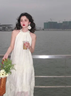 Light apricot off-white halter neck lace maxi dress with flowing tiered skirt styled by the waterfront with iced coffee and woven flower basket
