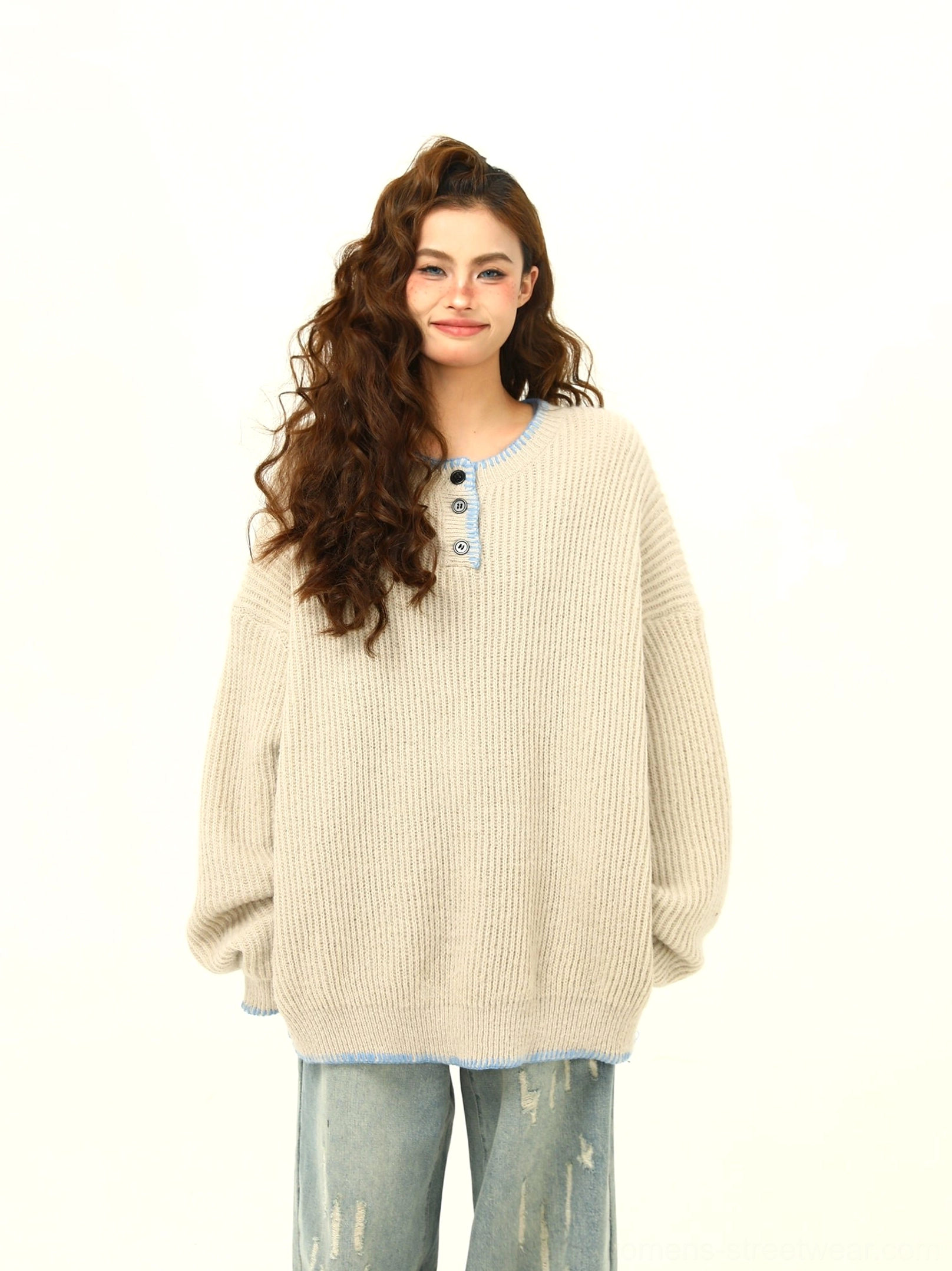 Apricot oversized Henley sweater with ribbed knit texture, contrast trim, and loose fit styled with wide-leg denim