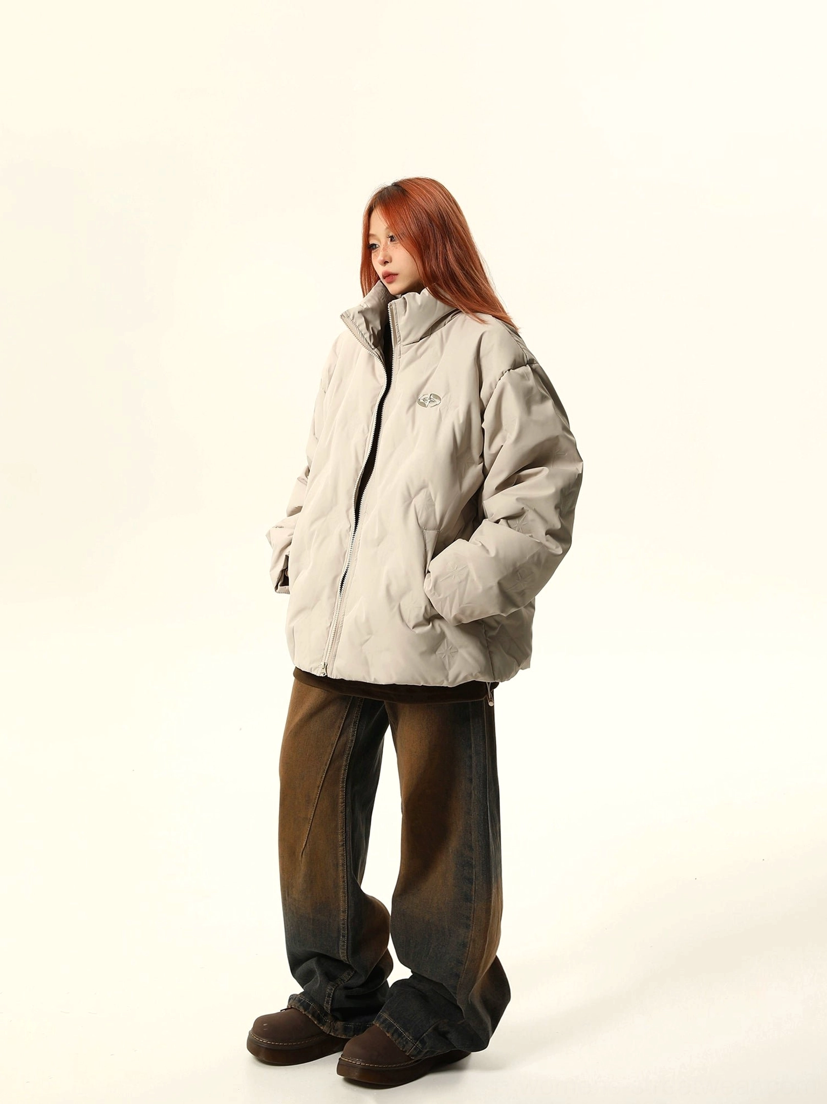 Side view of an apricot oversized quilted bomber jacket with front zipper, stand collar, hidden pockets, and loose fit