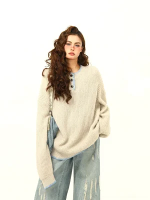 Apricot oversized ribbed Henley knit sweater with light blue contrast trim styled with distressed wide-leg jeans