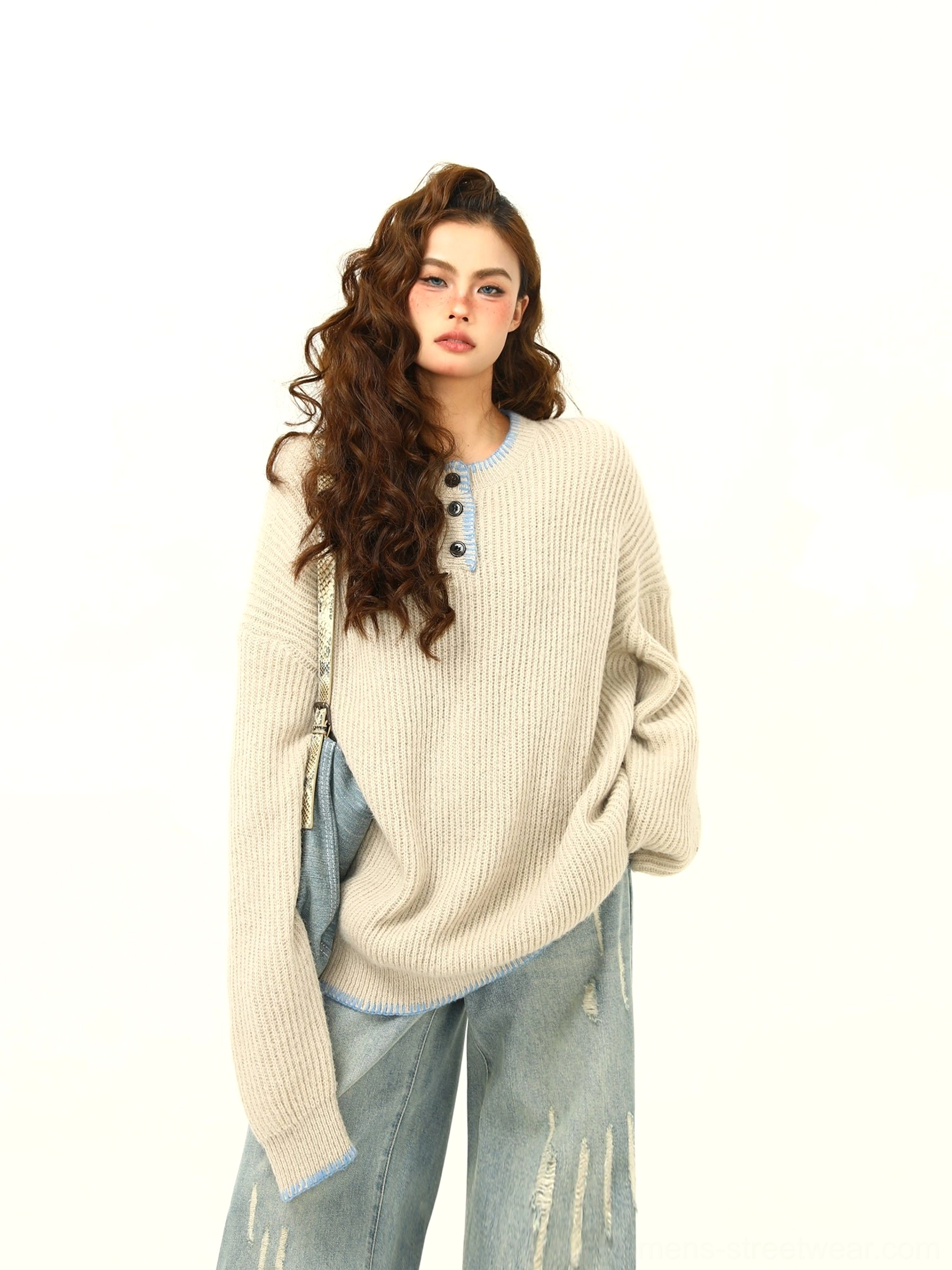 Apricot oversized ribbed Henley knit sweater with light blue contrast trim styled with distressed wide-leg jeans