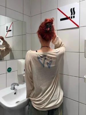 Back view of apricot oversized graphic long sleeve tee featuring heart and handwritten style print details