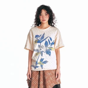 Apricot sesame leaf burnout graphic T-shirt with vintage botanical print, loose streetwear fit, and distressed rolled edges styled with a plaid skirt