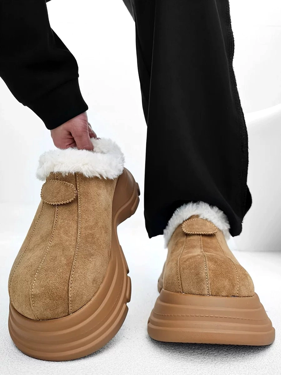 Apricot-tan suede-finish winter platform clog held in hand showing the fluffy faux-fur collar, rounded toe, and decorative vamp tab