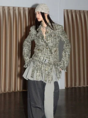 Apricot textured tweed fringe blazer shown from a three-quarter angle with button front, metallic waist belt, layered necklaces, and wide-leg dark denim