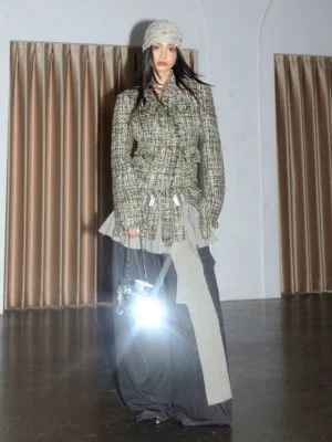 Apricot tweed fringe blazer jacket styled with a metallic waist belt, beige knit beanie, silver crossbody bag, and pointed heels in a full-body studio look