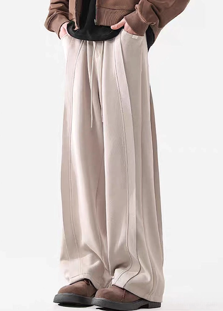 Slight side front view of Apricot wide-leg streetwear pants with adjustable drawstring waist and vertical seam lines