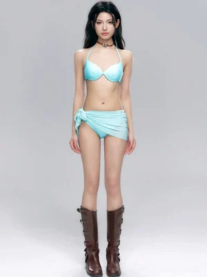 Front view of an aqua blue halter bikini set with push-up top, tie-side bottoms, knotted wrap swim skirt, and brown retro mid-calf boots