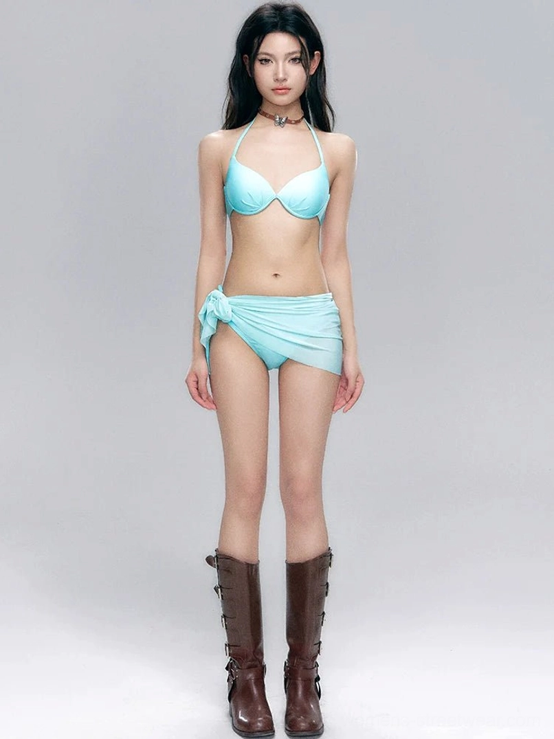 Front view of an aqua blue halter bikini set with push-up top, tie-side bottoms, knotted wrap swim skirt, and brown retro mid-calf boots