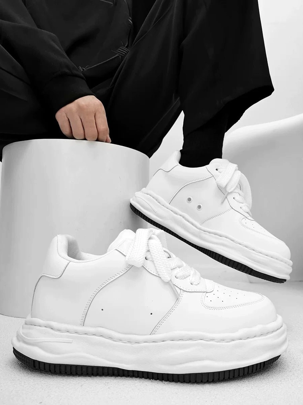 Arctic Crest white chunky platform skate sneakers with black outsole worn with black streetwear outfit in studio