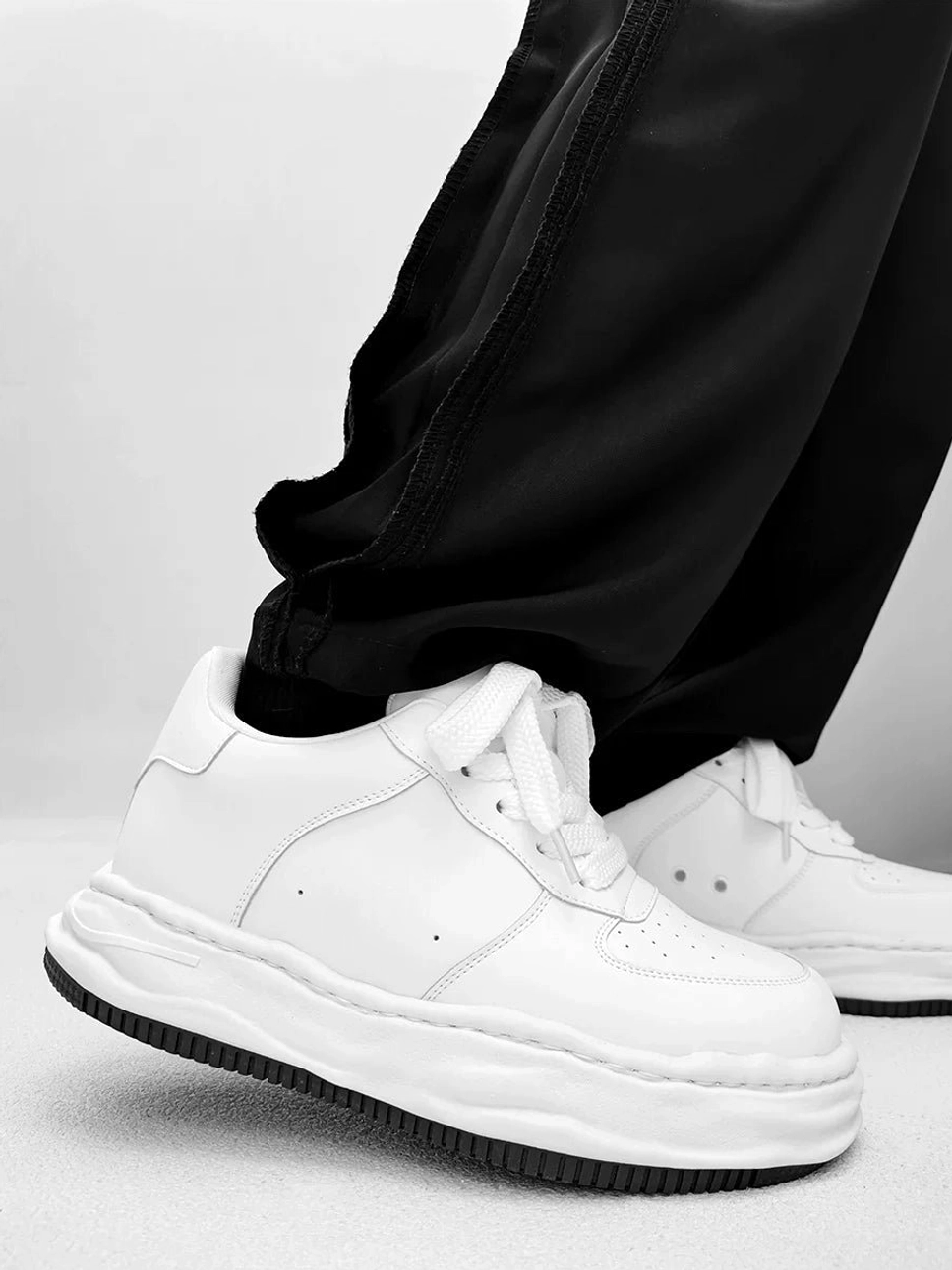 Arctic Crest white low-top platform skate sneakers with wavy sole worn with black cargo pants