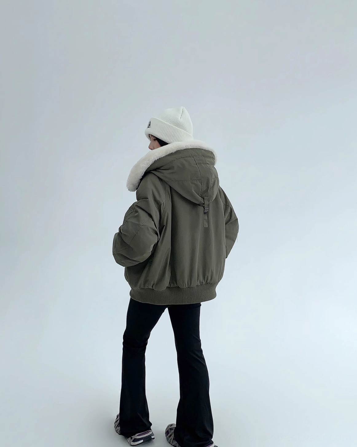 Back view of army green oversized bomber jacket with attached drawcord hood, seamless back panel, ribbed hem, and cuffs