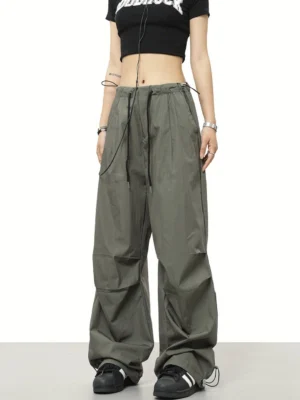 Army green parachute wide-leg streetwear pants with adjustable drawstring waist and cinch ankles styled with a black cropped top and sneakers